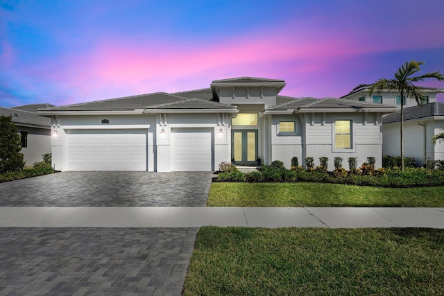 view of front of property with french doors, decorative driveway, an attached garage, stucco siding, and a tile roof
