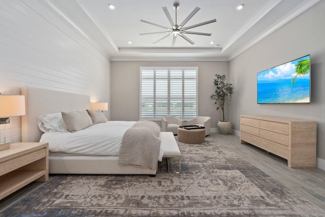 bedroom featuring wood finished floors, a raised ceiling, a ceiling fan, baseboards, and recessed lighting