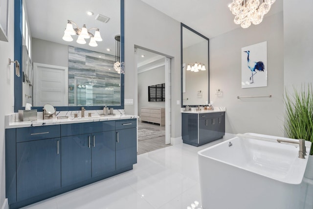 full bath with a chandelier, a stall shower, two vanities, a freestanding tub, and recessed lighting