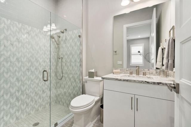 bathroom featuring a shower stall, toilet, and vanity