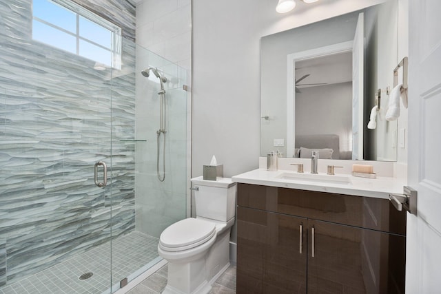 bathroom featuring a stall shower, toilet, vanity, and a ceiling fan