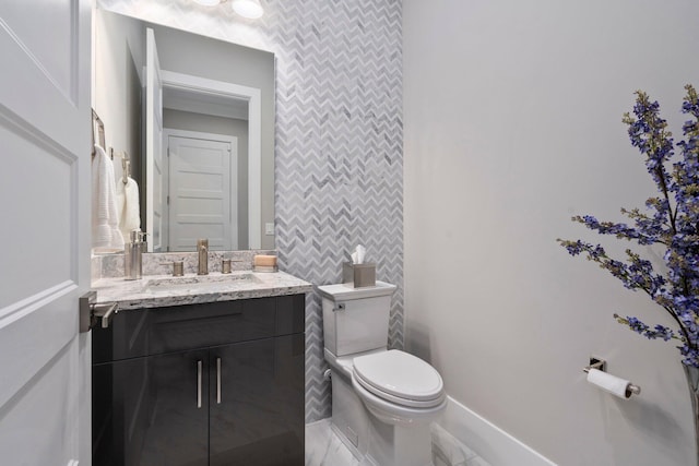bathroom featuring toilet, vanity, and baseboards