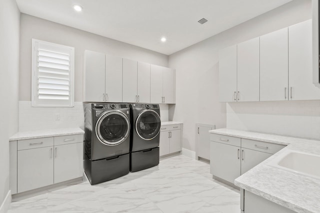 laundry area featuring washing machine and dryer, light marble finish floors, cabinet space, recessed lighting, and baseboards