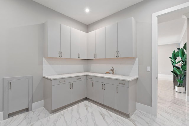kitchen with gray cabinetry, light marble finish floors, baseboards, a sink, and recessed lighting