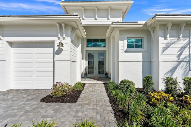 doorway to property with french doors, an attached garage, and driveway