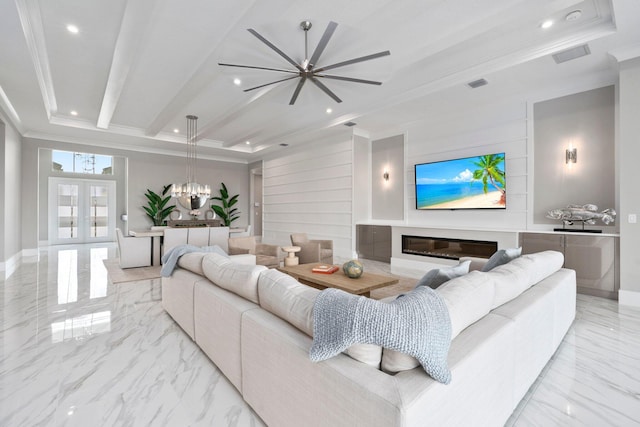 living area with crown molding, light marble finish floors, a raised ceiling, recessed lighting, and a glass covered fireplace