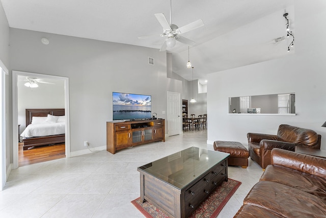 living room featuring a ceiling fan, high vaulted ceiling, light tile patterned floors, and baseboards