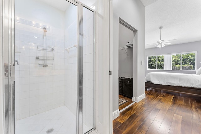 bathroom featuring hardwood / wood-style floors, ceiling fan, connected bathroom, a stall shower, and baseboards