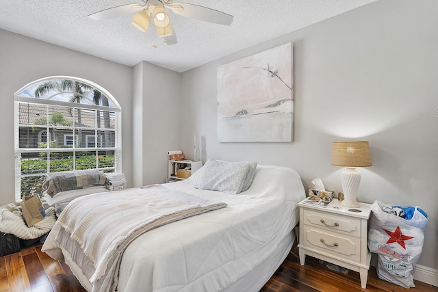bedroom with a textured ceiling, dark wood-style flooring, and a ceiling fan