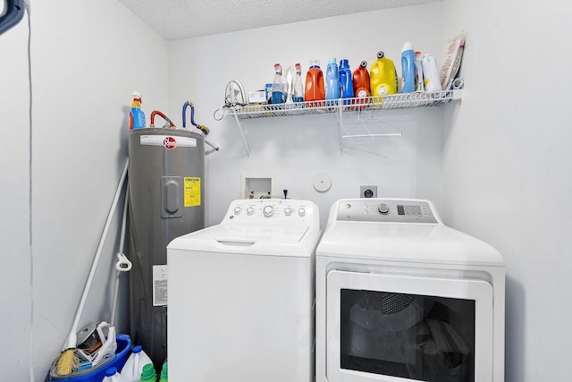 clothes washing area featuring washing machine and dryer, water heater, and a textured ceiling