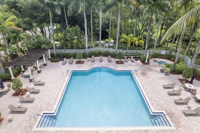 community pool with fence, a patio area, and view of scattered trees