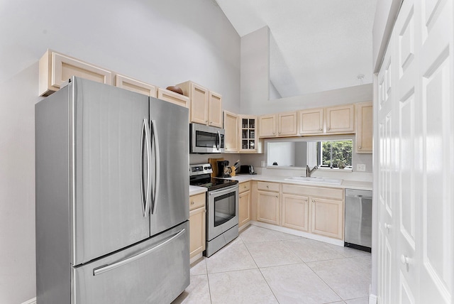 kitchen featuring appliances with stainless steel finishes, light brown cabinets, a sink, light countertops, and high vaulted ceiling