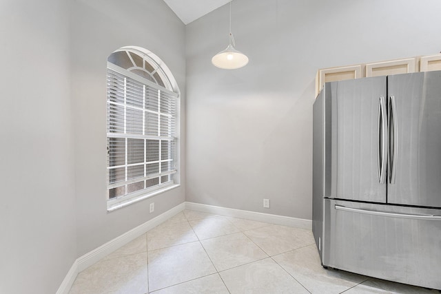 unfurnished dining area featuring light tile patterned flooring, baseboards, and vaulted ceiling