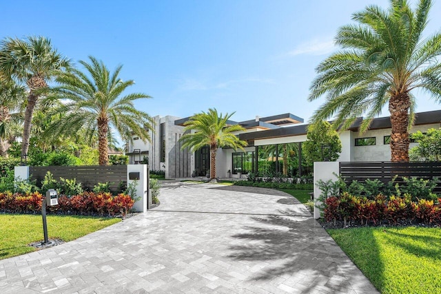4460 NE 31st Ave, Lighthouse Point, FL 33064 - modern home featuring a fenced front yard, a gate, stucco siding, and decorative driveway