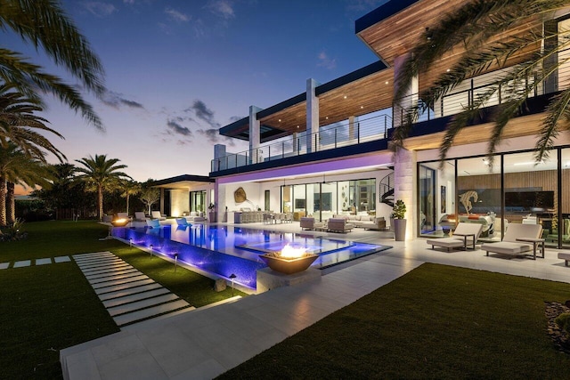 4460 NE 31st Ave, Lighthouse Point, FL 33064 - back of house at dusk with a balcony, an outdoor living space, a patio area, and an infinity pool