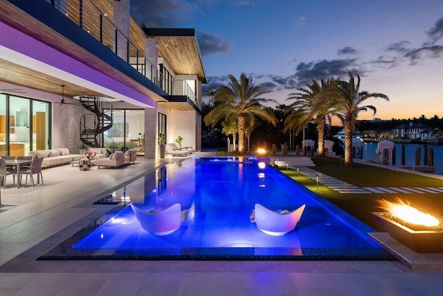 4460 NE 31st Ave, Lighthouse Point, FL 33064 - pool at dusk featuring a patio area, an outdoor pool, stairway, and an outdoor living space with a fire pit