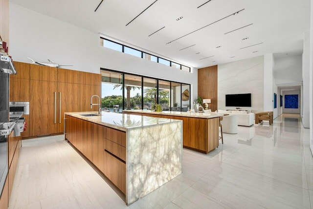 4460 NE 31st Ave, Lighthouse Point, FL 33064 - kitchen featuring modern cabinets, a high ceiling, a large island with sink, a sink, and brown cabinets
