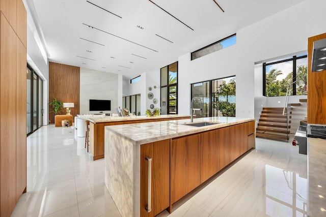 4460 NE 31st Ave, Lighthouse Point, FL 33064 - kitchen with a sink, modern cabinets, a high ceiling, brown cabinetry, and a spacious island