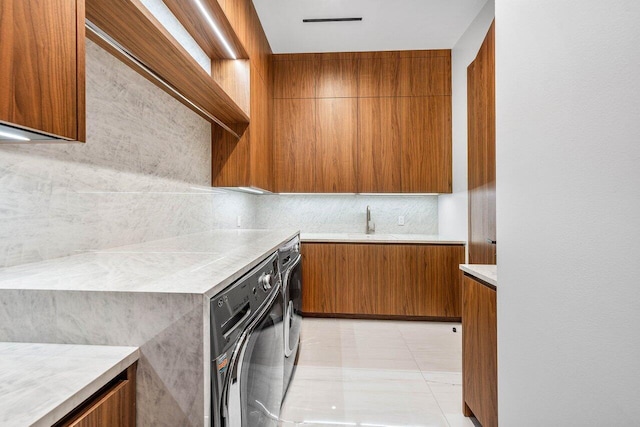 4460 NE 31st Ave, Lighthouse Point, FL 33064 - kitchen featuring brown cabinetry, light countertops, separate washer and dryer, modern cabinets, and tasteful backsplash