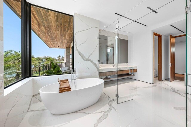 4460 NE 31st Ave, Lighthouse Point, FL 33064 - bathroom featuring a soaking tub, marble tiled floors, and vanity