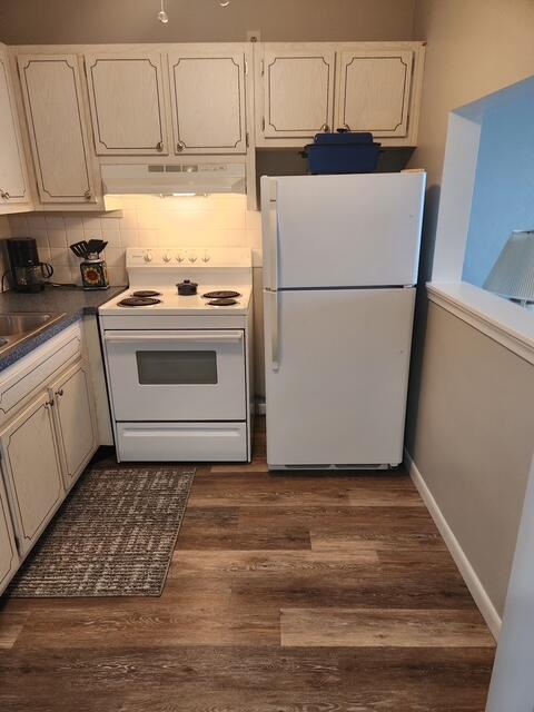 3362 Cynthia Ln Unit 211, Lake Worth Beach, FL 33461 - kitchen with white appliances, under cabinet range hood, decorative backsplash, and dark wood finished floors