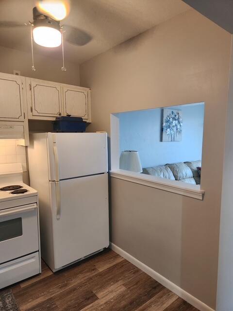 3362 Cynthia Ln Unit 211, Lake Worth Beach, FL 33461 - kitchen with white appliances, dark wood-style floors, exhaust hood, white cabinets, and baseboards