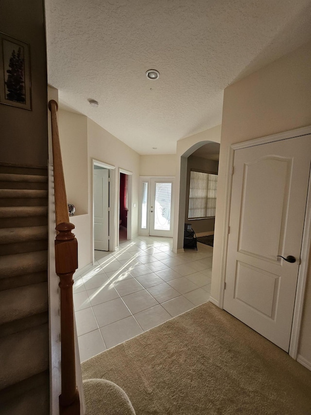 1639 SW Harbour Isles Cir Unit 29, Port Saint Lucie, FL 34986 - corridor featuring arched walkways, light tile patterned floors, a textured ceiling, stairway, and light colored carpet