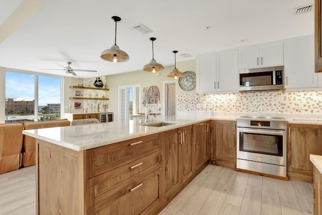 kitchen featuring appliances with stainless steel finishes, a sink, light wood-style floors, and decorative backsplash