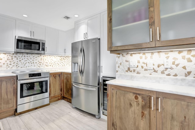 kitchen featuring stainless steel appliances, light countertops, glass insert cabinets, white cabinetry, and recessed lighting