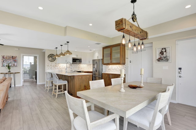 dining space with light wood-type flooring, recessed lighting, and baseboards