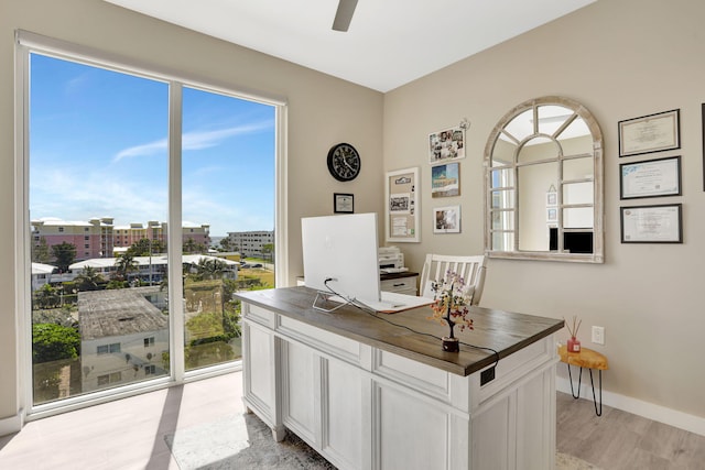 office space with healthy amount of natural light, ceiling fan, and light wood finished floors