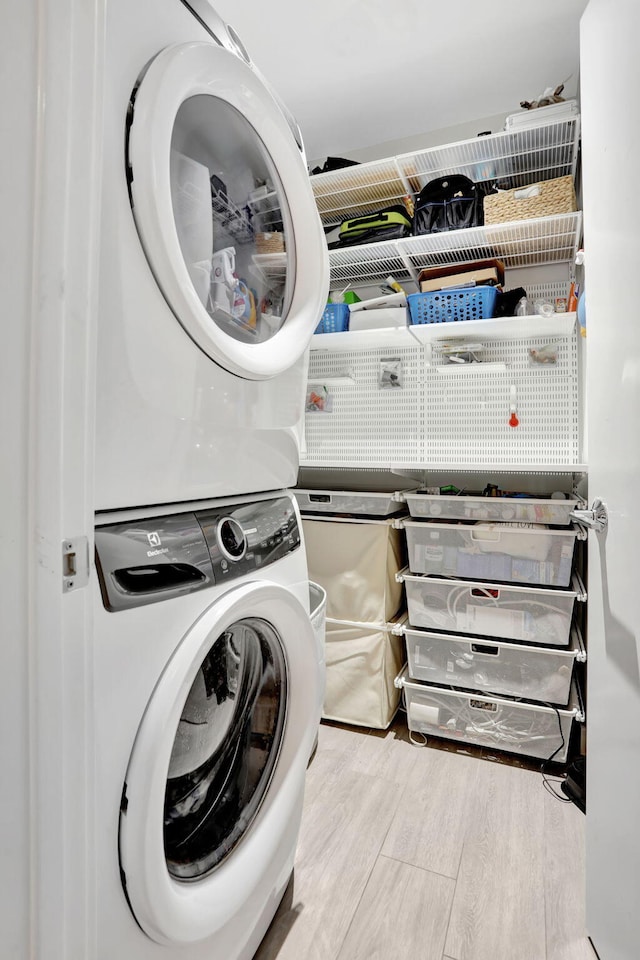 washroom with stacked washer / dryer and wood finished floors