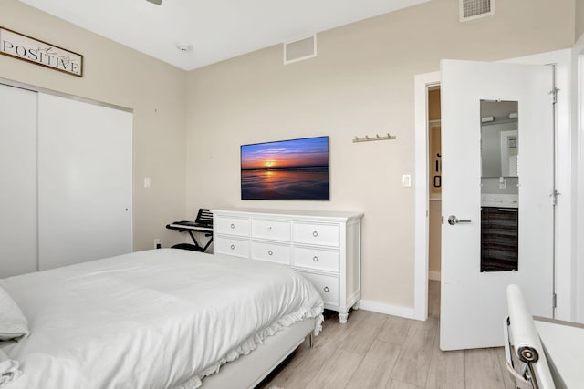 bedroom featuring light wood finished floors, baseboards, and a closet