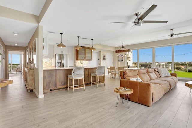 living area featuring light wood finished floors, a ceiling fan, and recessed lighting