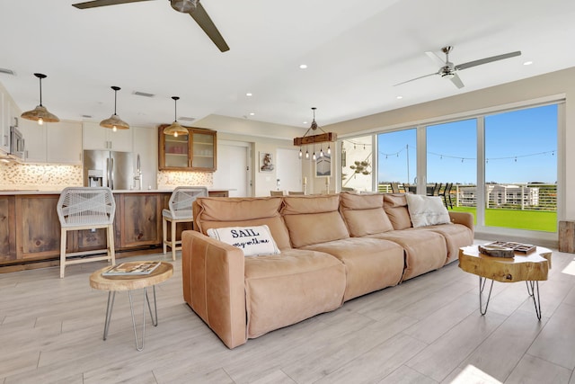 living area featuring ceiling fan, light wood-type flooring, and recessed lighting