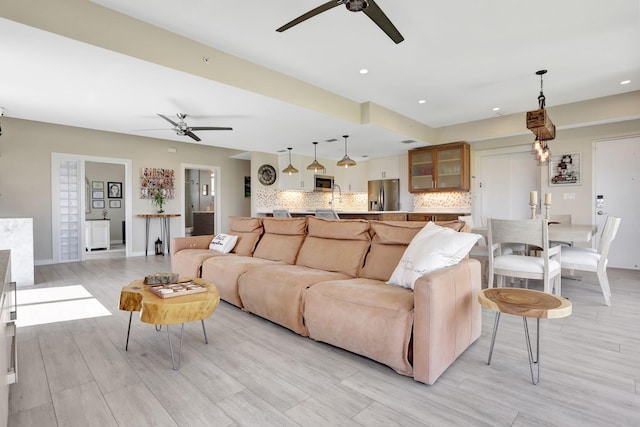 living area featuring a ceiling fan, light wood-style flooring, recessed lighting, and baseboards