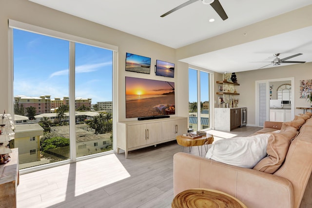 living room with a ceiling fan, light wood-style flooring, beverage cooler, recessed lighting, and baseboards