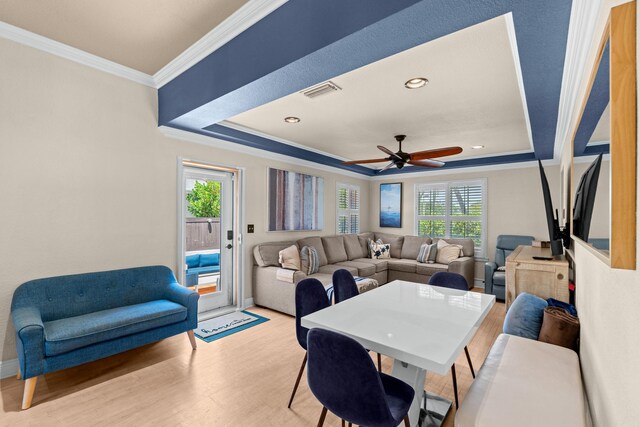 dining area with ornamental molding, light wood-type flooring, a tray ceiling, ceiling fan, and baseboards