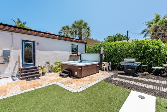 rear view of house with a hot tub, stucco siding, entry steps, a tiled roof, and a patio