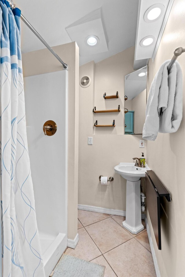 full bathroom with a shower stall, tile patterned flooring, baseboards, and a sink