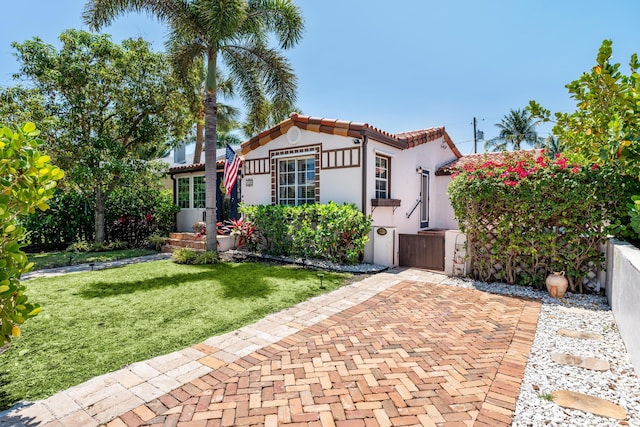 mediterranean / spanish-style house featuring stucco siding, a gate, and a tile roof