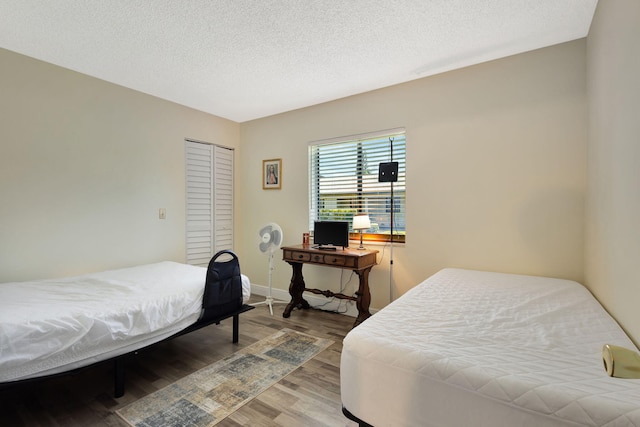bedroom with light wood finished floors, a closet, a textured ceiling, and baseboards