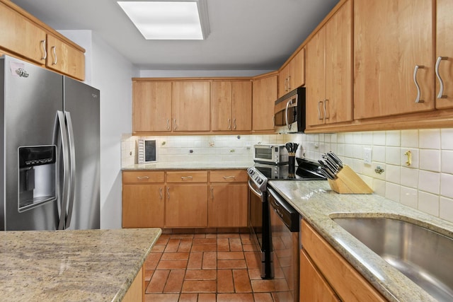 kitchen featuring appliances with stainless steel finishes, backsplash, and light stone countertops