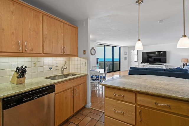 kitchen with stainless steel dishwasher, a sink, tasteful backsplash, and light stone countertops
