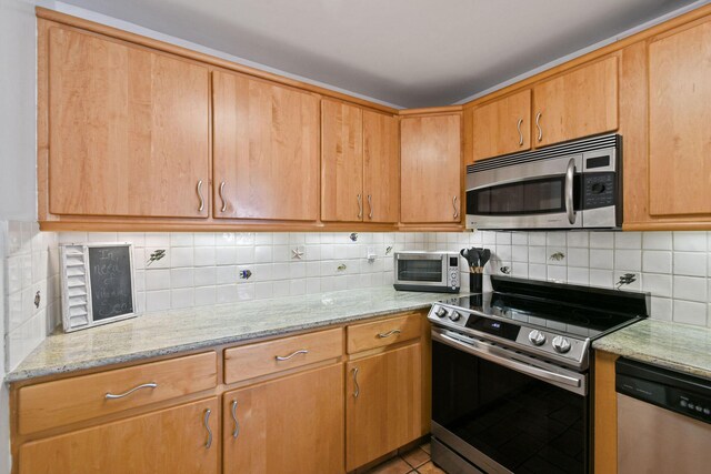 kitchen with stainless steel appliances, decorative backsplash, and light stone countertops