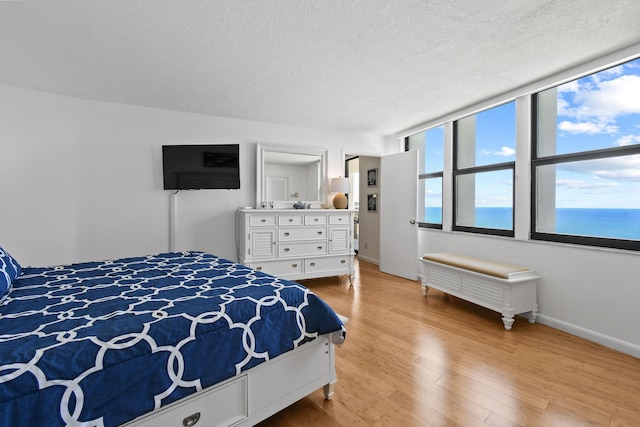 bedroom featuring a textured ceiling, light wood-style floors, and baseboards