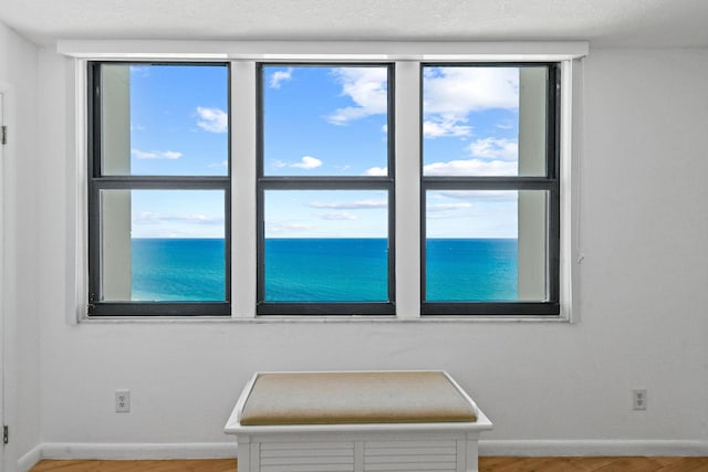 empty room with wood finished floors, baseboards, and a water view