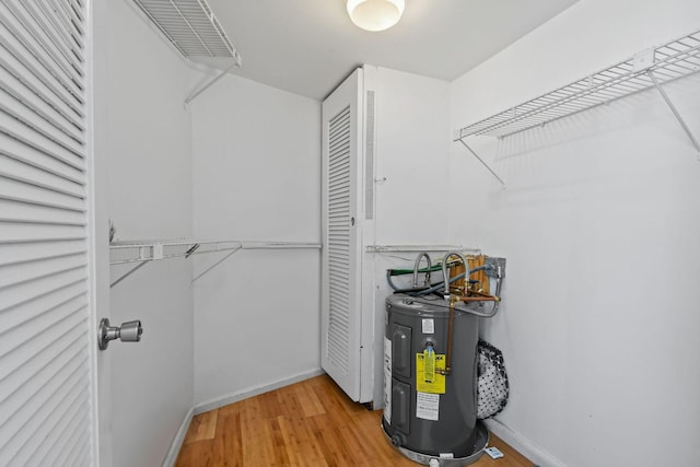 walk in closet with electric water heater and wood finished floors