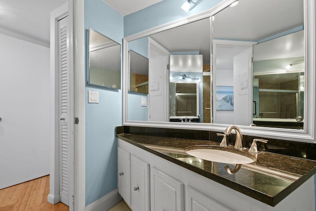 full bathroom with wood finished floors, vanity, and tiled shower