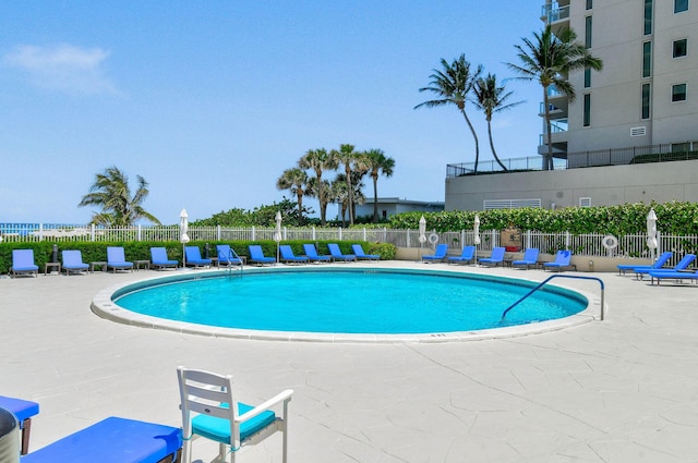 community pool with fence and a patio area